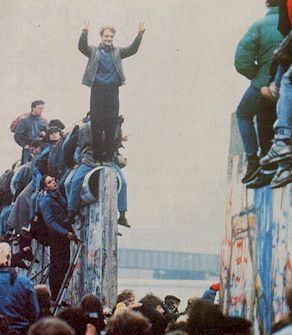 A photo of Berliners celebrating on the partially destroyed Berlin Wall.