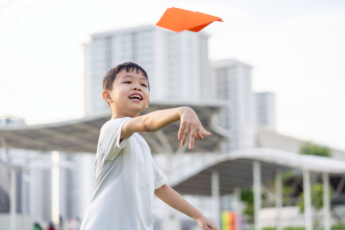 Un enfant qui applique une force sur un avion de papier pour le mettre en mouvement