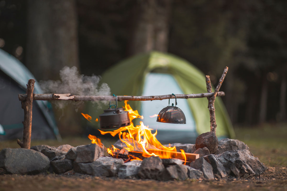 Un feu de camp chauffe l’eau d’une bouilloire.