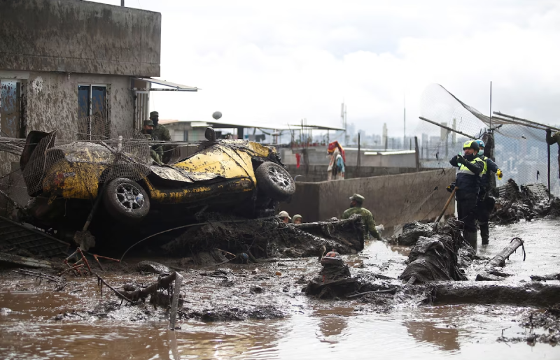 Photographie montrant une rue recouverte de boue et une voiture renversée.