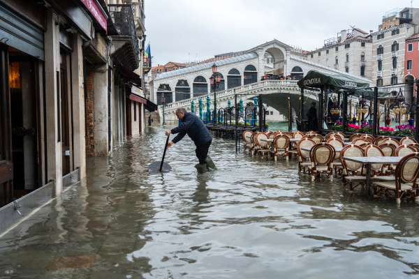 Photographie d’un homme debout les pieds dans l’eau sur une terrasse.
