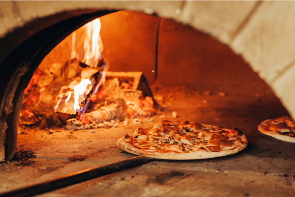 Une photographie d’une pizza en cuisson dans un four.