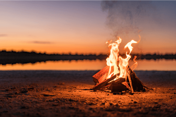 A photograph of a fire by the water.