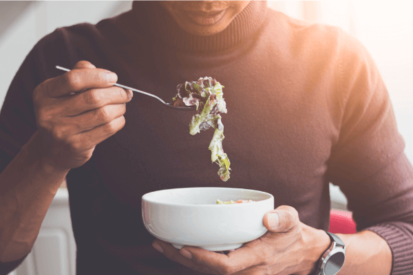 A photograph of a person eating a salad.