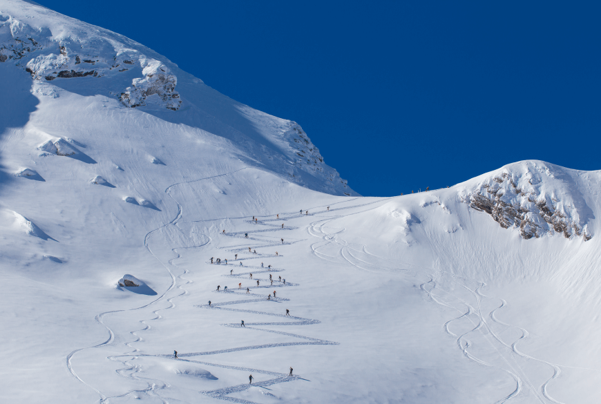 Backcountry skiers climbing a mountain on an s-shaped route.