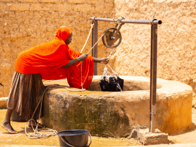 A well with a rope attached to a bucket of water and a pulley.