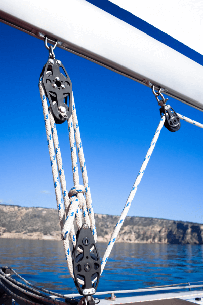 A sailboat's downhaul is a rope that passes through several fixed and movable pulleys to hold the boom in place.