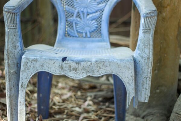 A broken and deteriorated plastic chair.