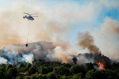 A helicopter flies over a forest fire.
