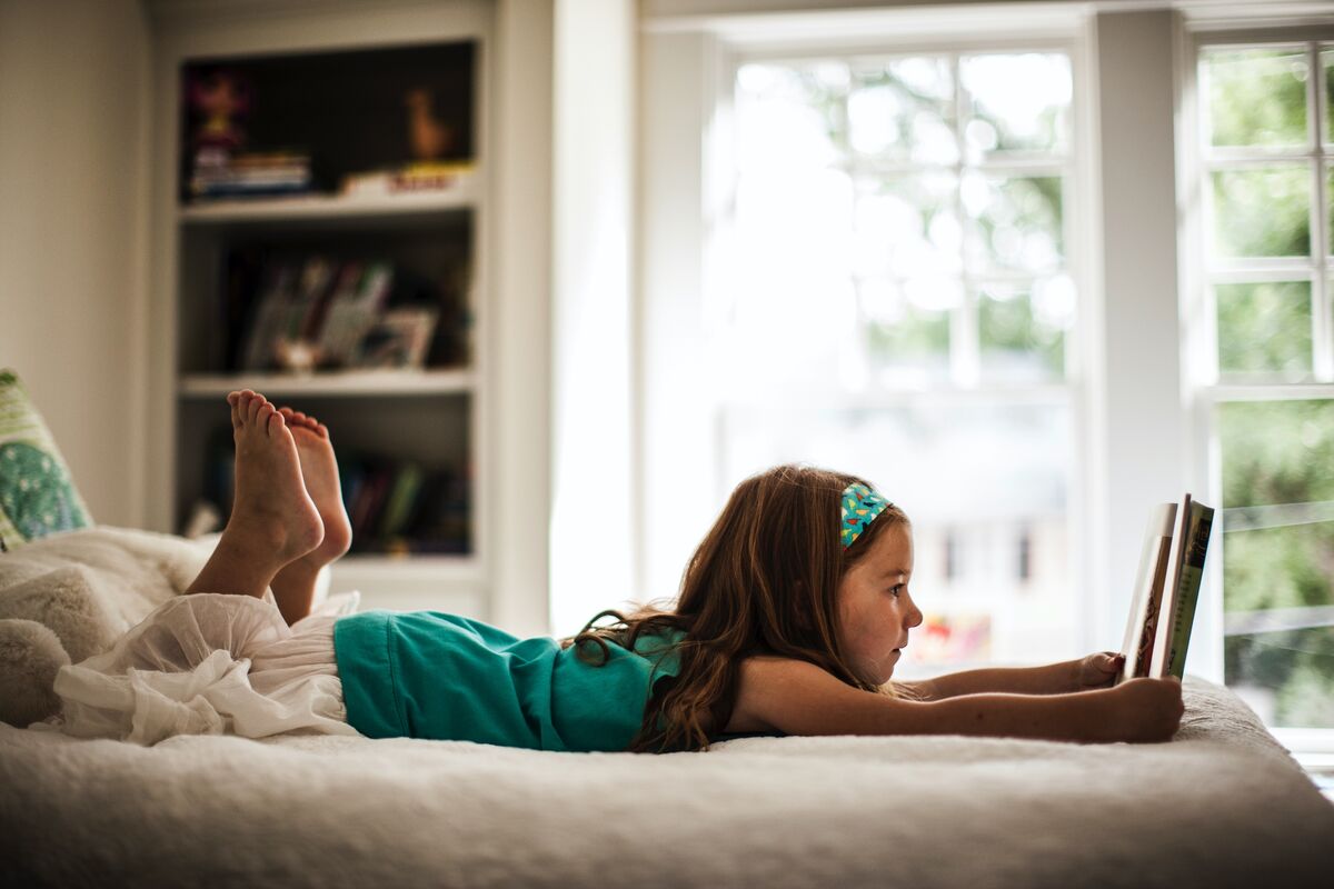 Une fille lisant un livre dans sa chambre.
