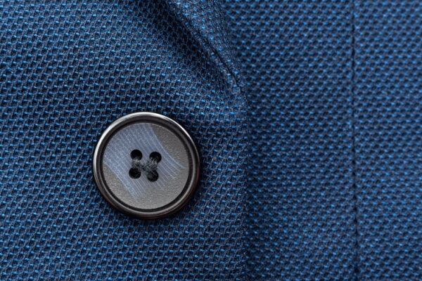 Image of a 4-hole button linked to a shirt by a thread.