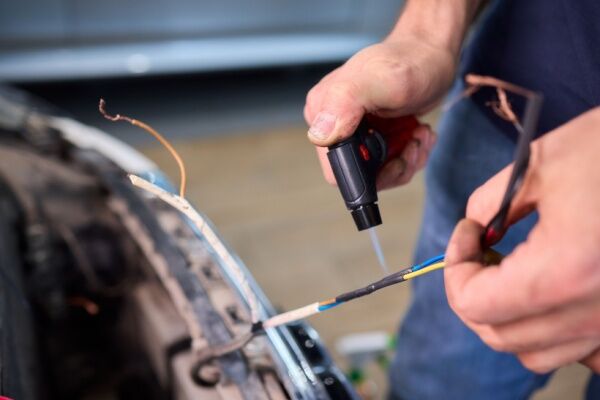 Image of two electrical wires wrapped in a plastic sheath being heated with a blowtorch.  