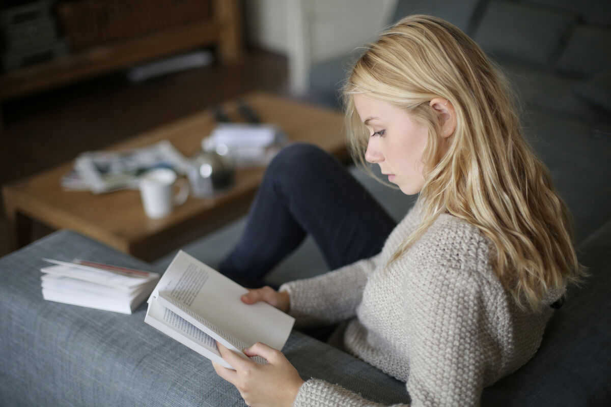 A teenager reading a book at home.