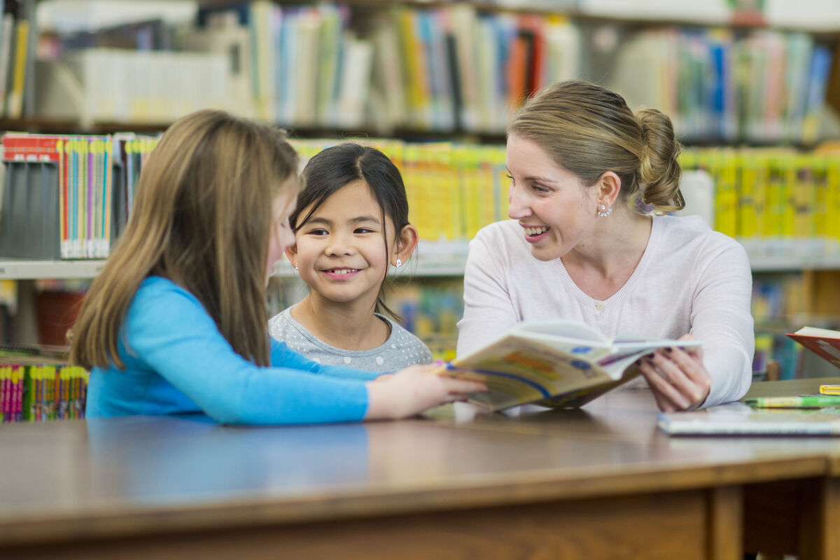 Une adulte à la bibliothèque avec deux enfants. 