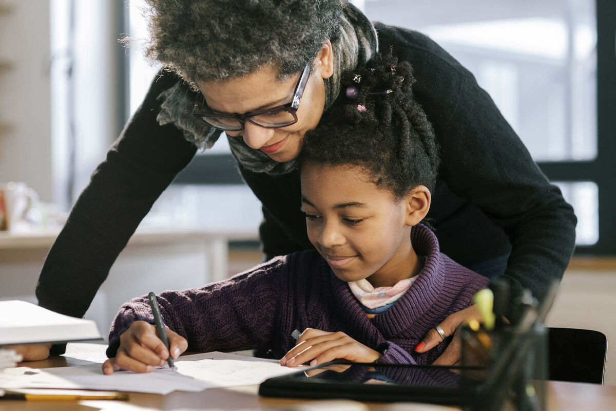Une mère aidant sa fille à faire ses devoirs.