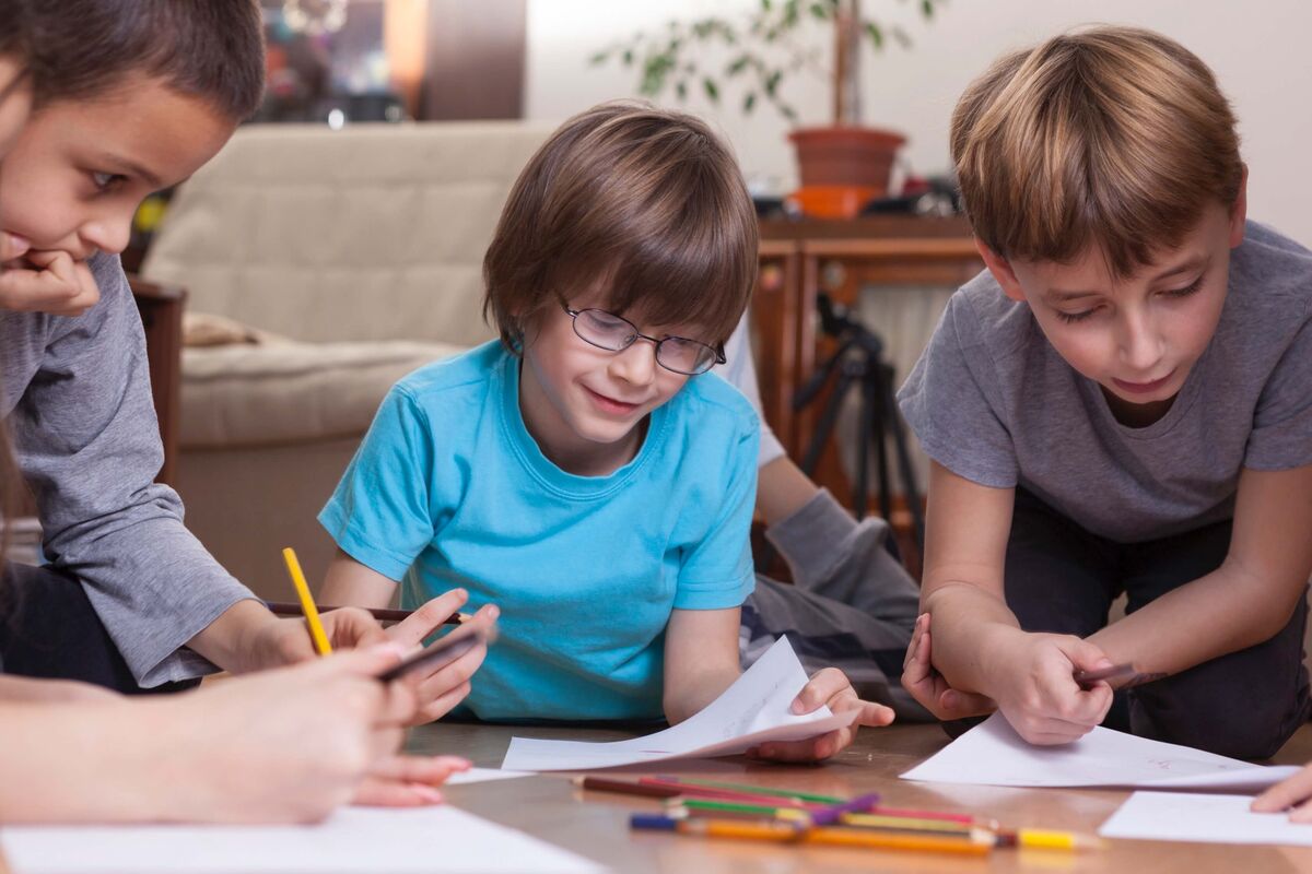 Plusieurs enfant faisant leur devoirs par terre.