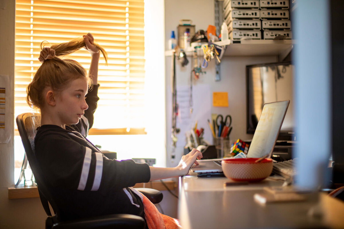 Une enfant faisant ses devoirs et se tirant doucement les cheveux.