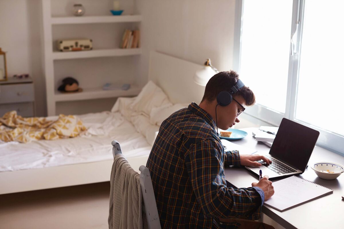 Un ado faisant ses devoirs dans sa chambre.
