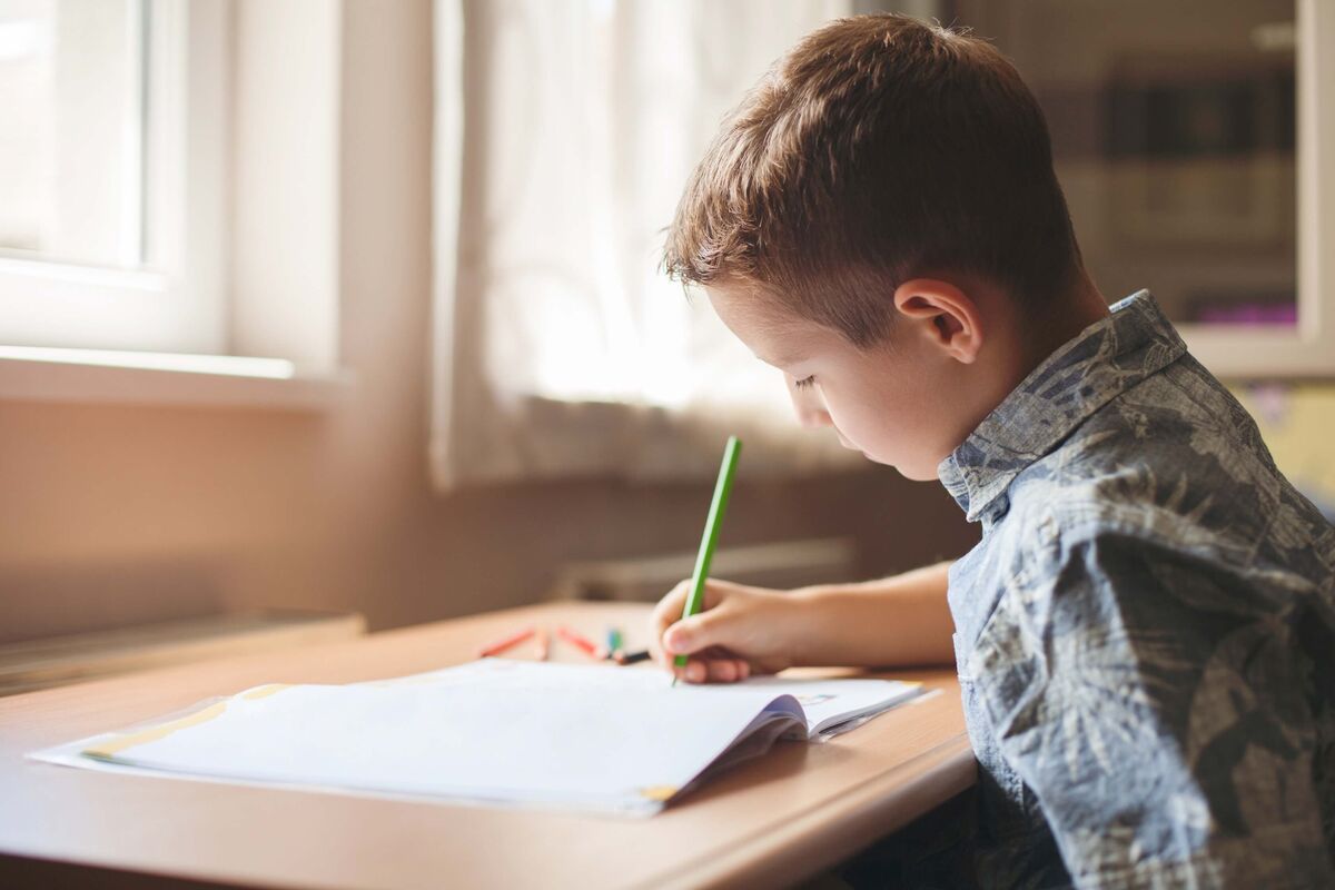 Un garçon faisant ses devoirs dans sa chambre.