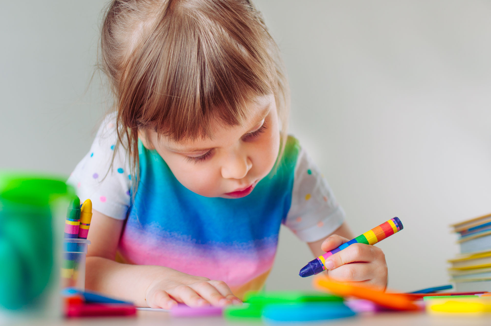 Une enfant dessine à l’aide d’un crayon de cire.
