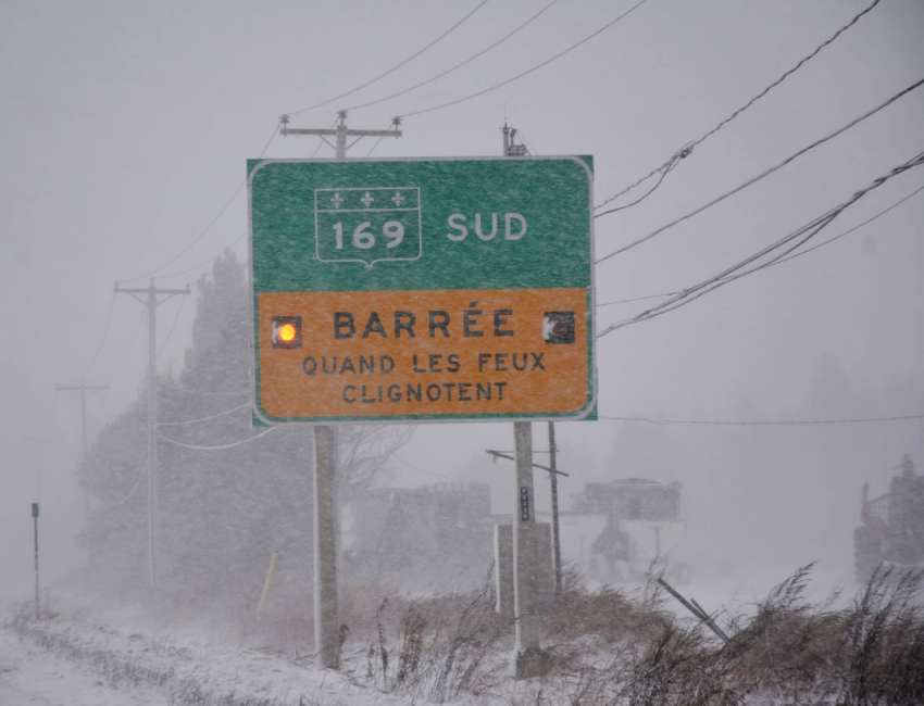 Photographie d’une affiche indiquant une route barrée.