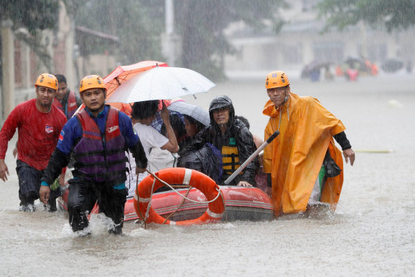 Des sauveteurs évacuent des résidents à Manille dans une rue inondée.