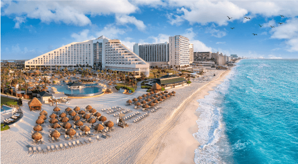 Photographie d’une plage de Cancún au Mexique avec des hôtels, une piscine et des chaises de plage.