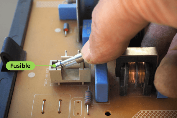 Une personne remplace le fusible d’un circuit électronique.