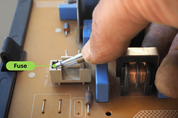 A person replaces a fuse in an electronic circuit.