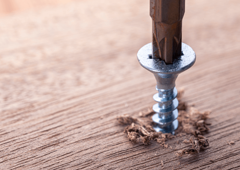 A screw screwed into the wood with a screwdriver.