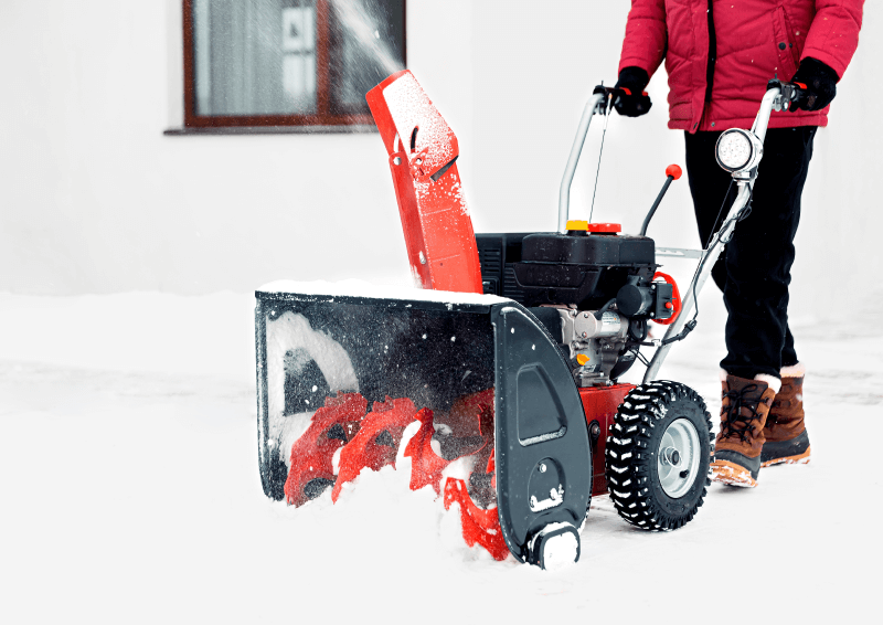 A person using the snow blower. The rotating screw on the snow blower moves the snow.