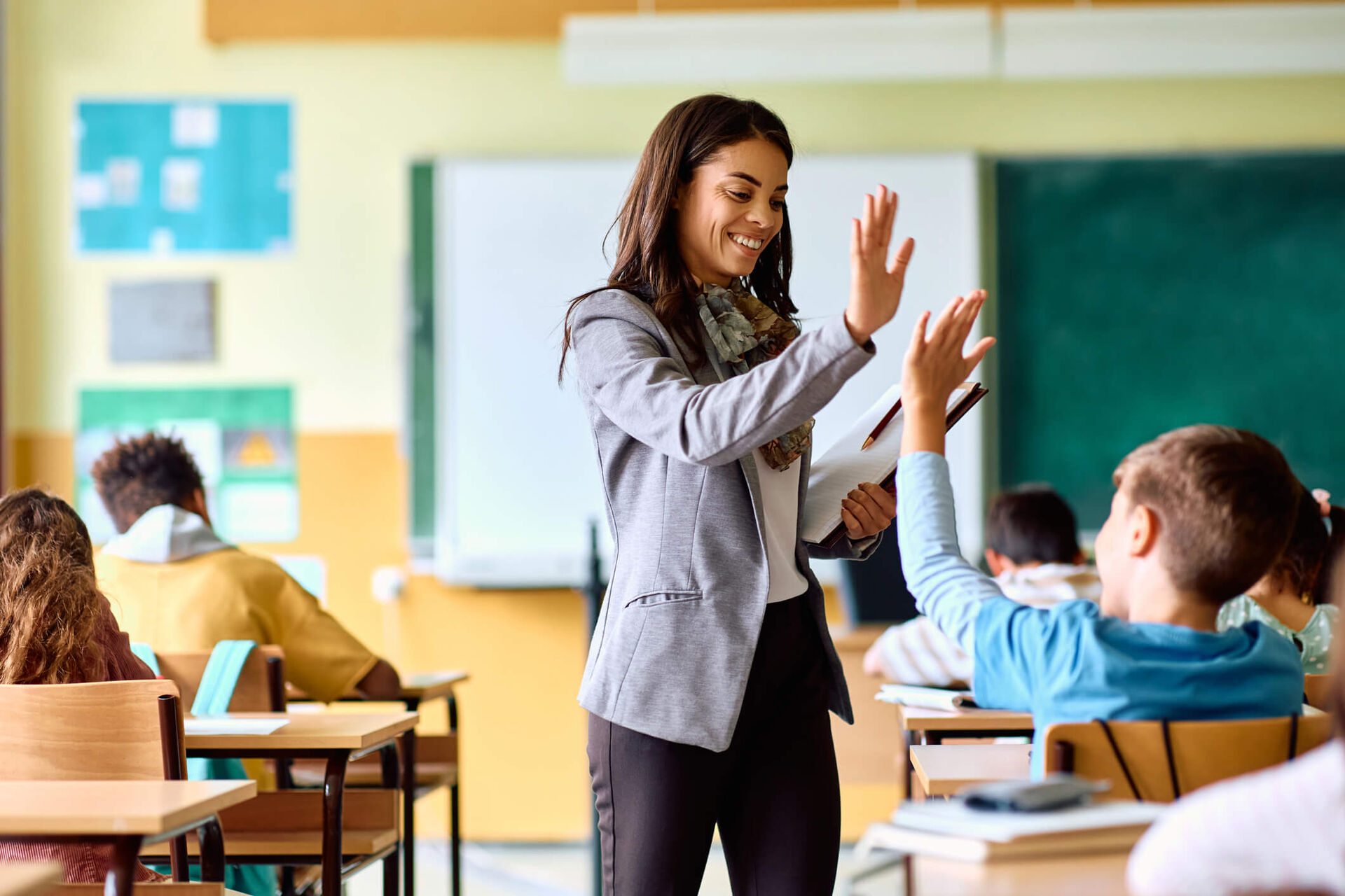 Une enseignante tape joyeusement dans la main d'un élève.