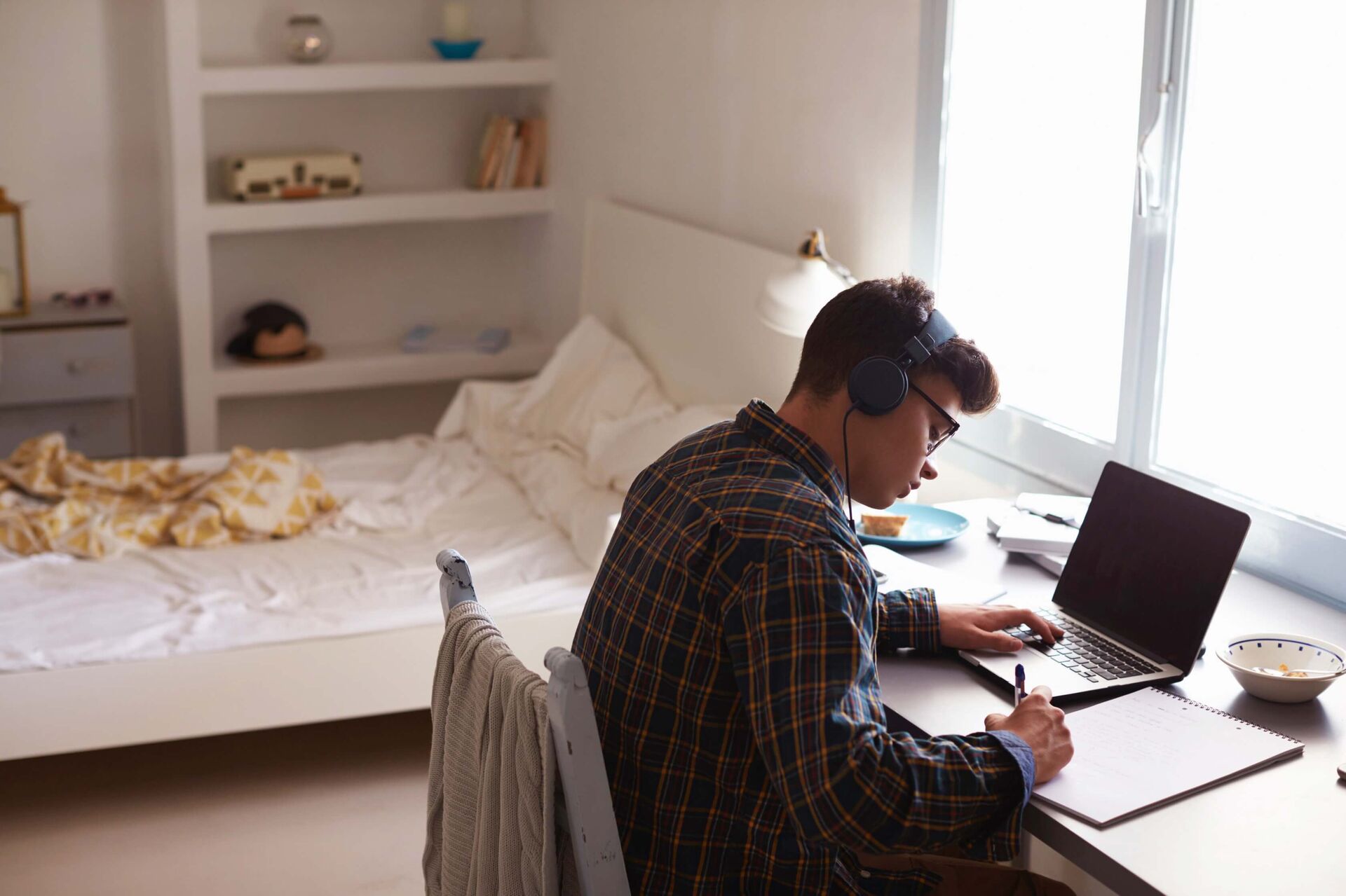 Un ado faisant ses devoirs dans sa chambre.
