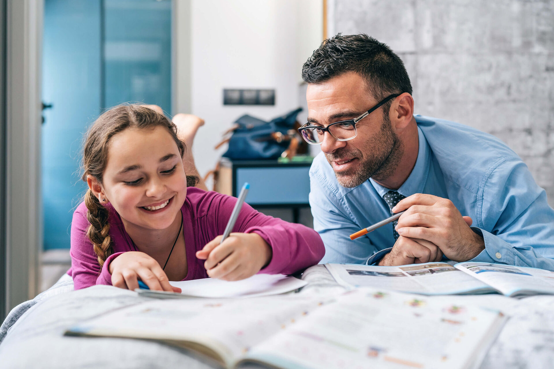 Un père aidant sa fille à faire un devoir.