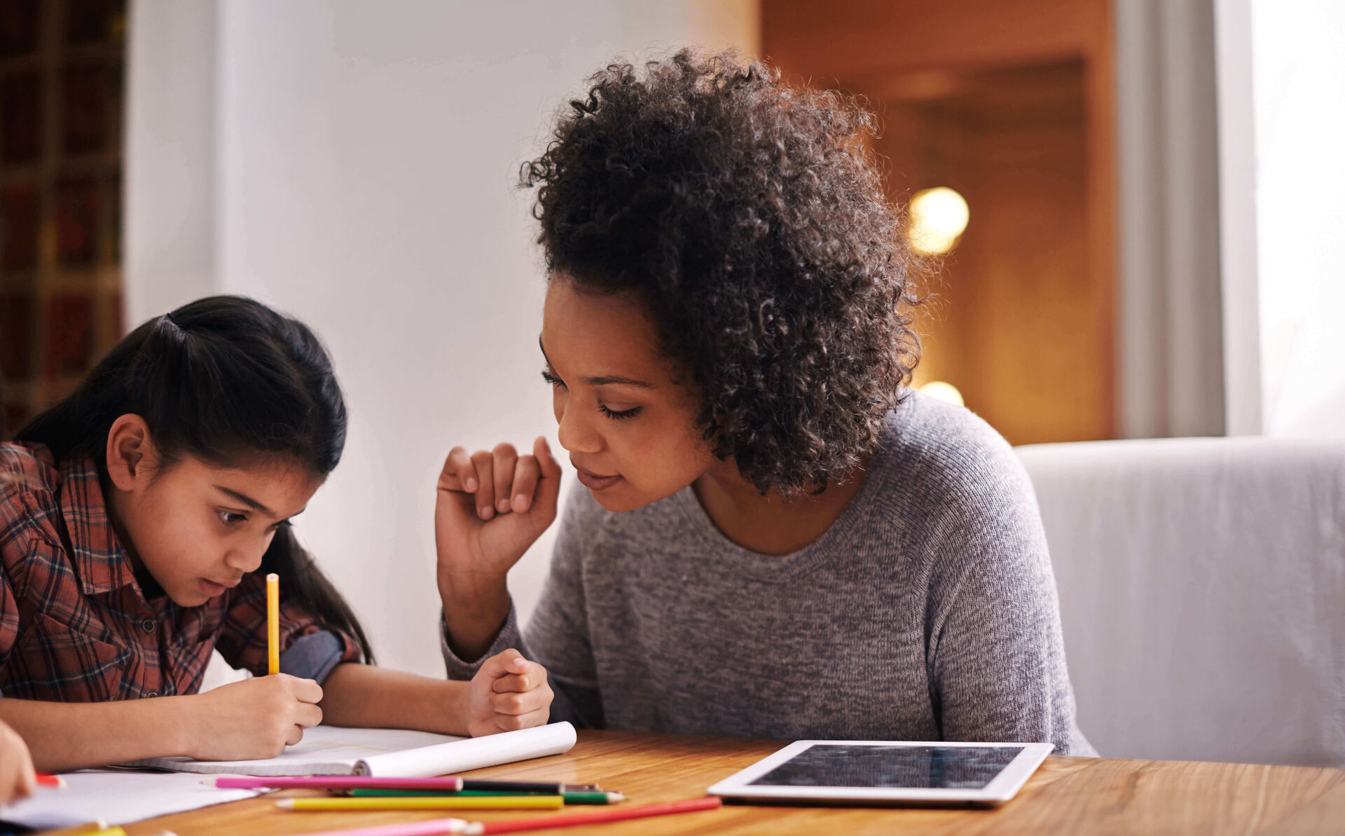 Une mère aidant son enfant à faire ses devoirs.