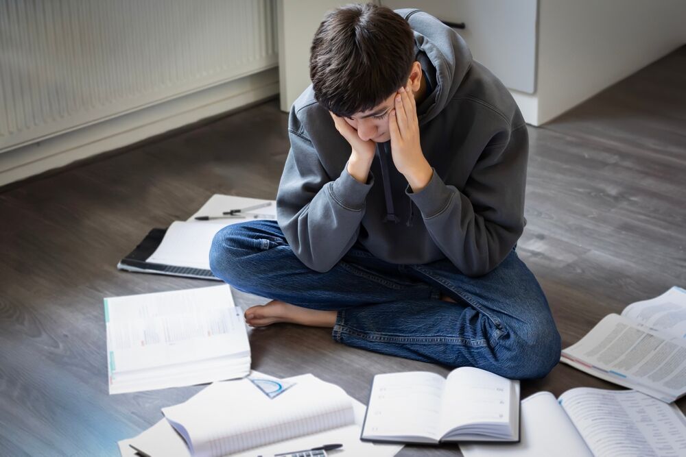 Un adolescent entouré de manuel scolaire.