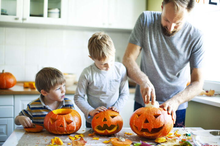 Un père préparant des citrouilles avec ses deux garçons.